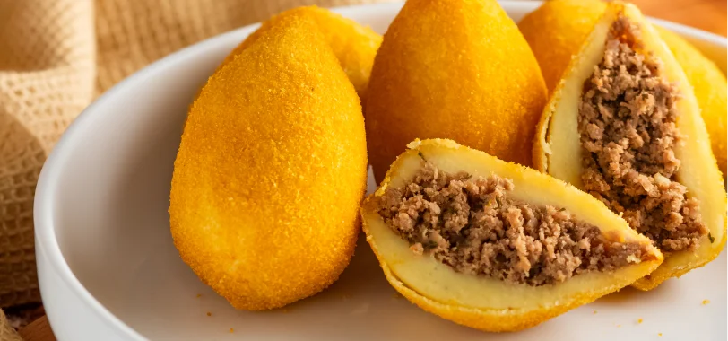 Coxinha de carne moída frita com massa dourada, aberta ao meio – Vó Linda Casa de Salgados