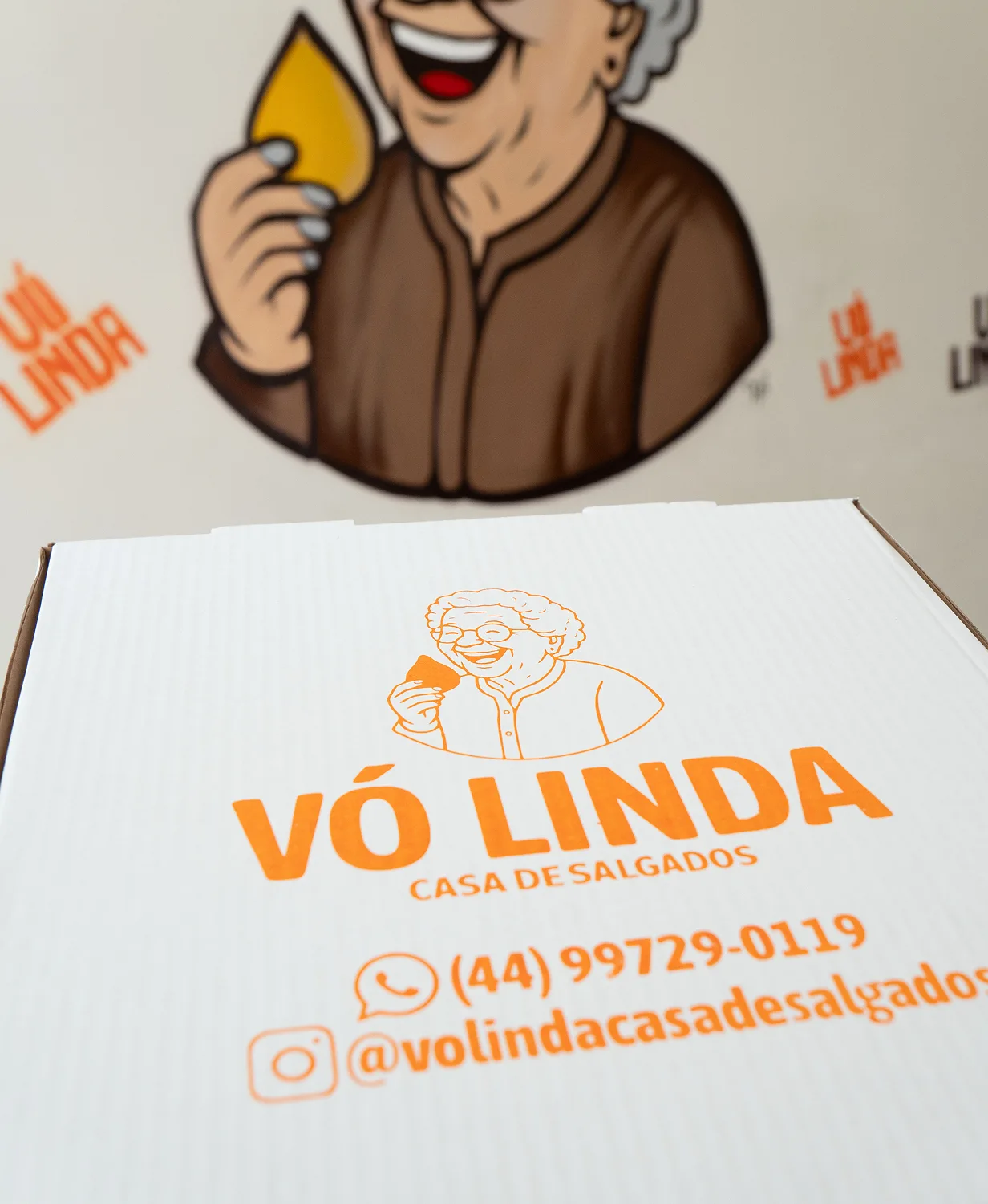 Caixa de salgados da Vó Linda Casa de Salgados com logo, contato (44) 99729-0119 e Instagram @volindacasadesalgados
