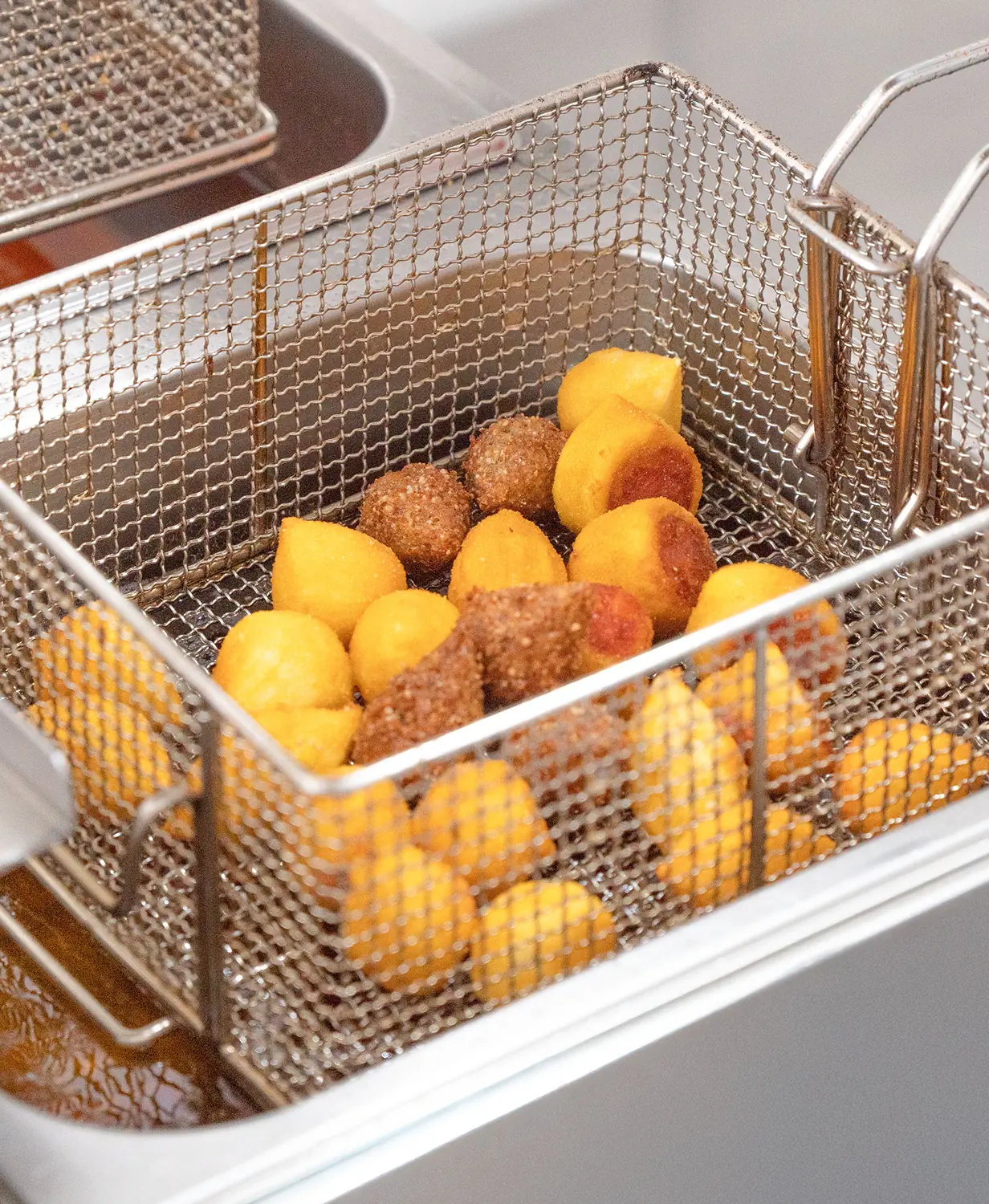 Coxinhas e bolinhos de queijo da Vó Linda Casa de Salgados sendo fritos em óleo na fritadeira profissional