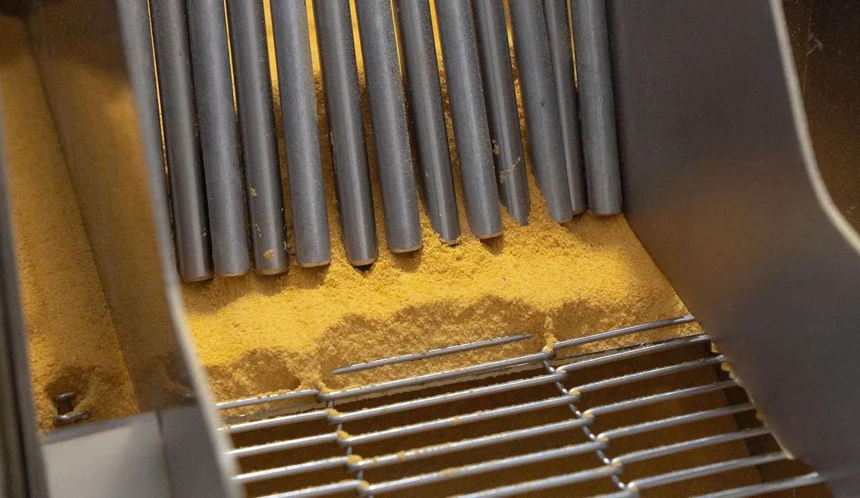 Máquina de empanamento com farinha de milho amarela na linha de produção da Vó Linda Casa de Salgados