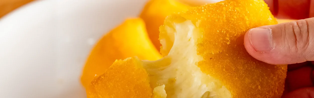 Mão segurando um salgado de travesseiro de queijo - Vó Linda Casa De Salgados
